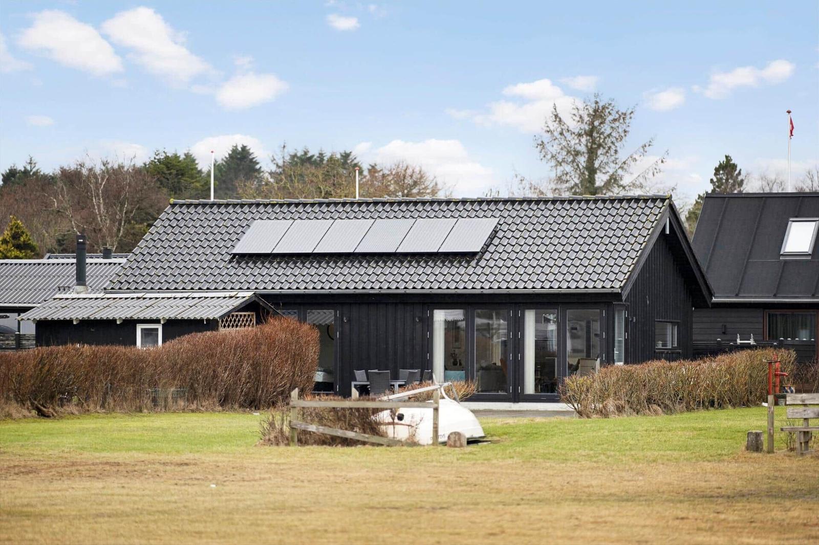 Black house with solar panels, terrace, and garden. Flag waving in the wind.