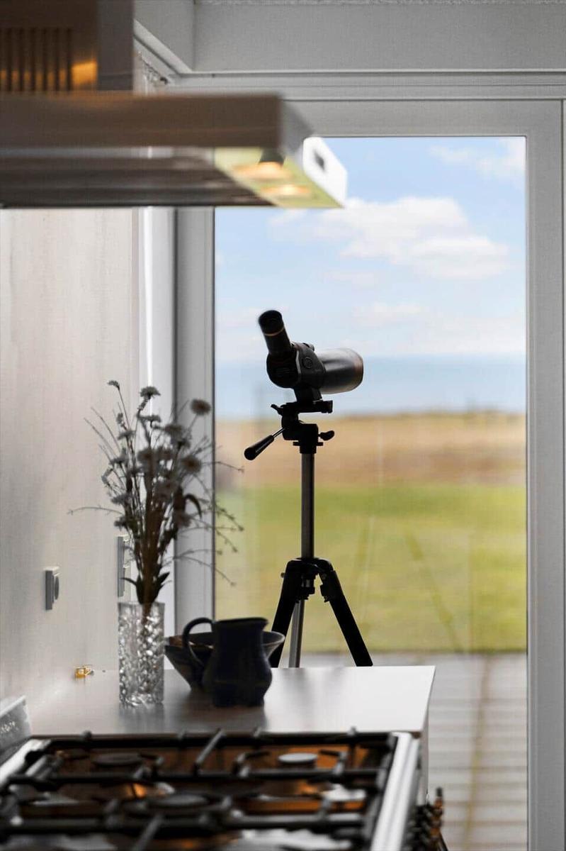 Telescope on tripod by window with view of landscape