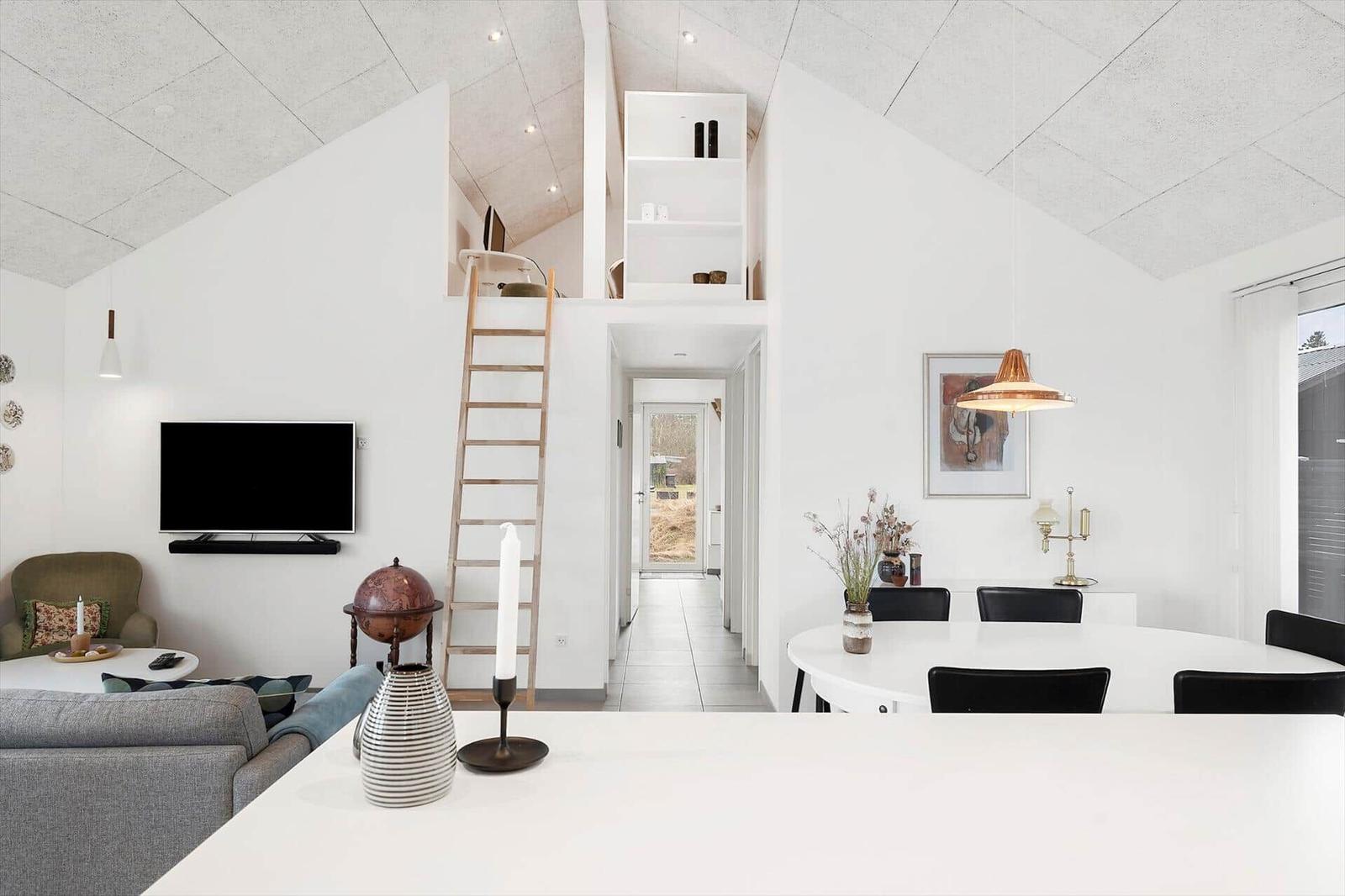 Living and dining area with loft, ladder, and TV.