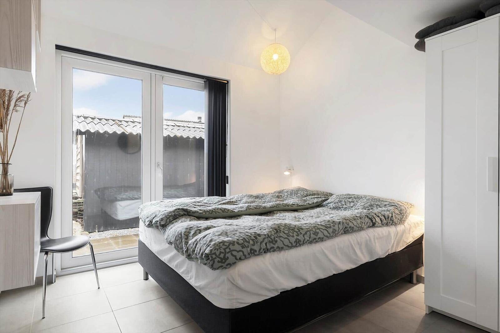 Bedroom with bed, wardrobe, and window to outdoor terrace.