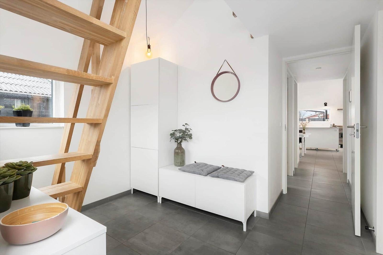 Entrance with wooden stairs, white cabinets, and gray floor. Hallway to the kitchen.