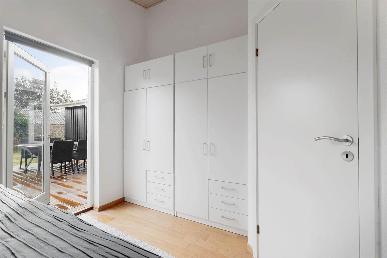 Schlafzimmer mit weißem Schrank und Terrassentür