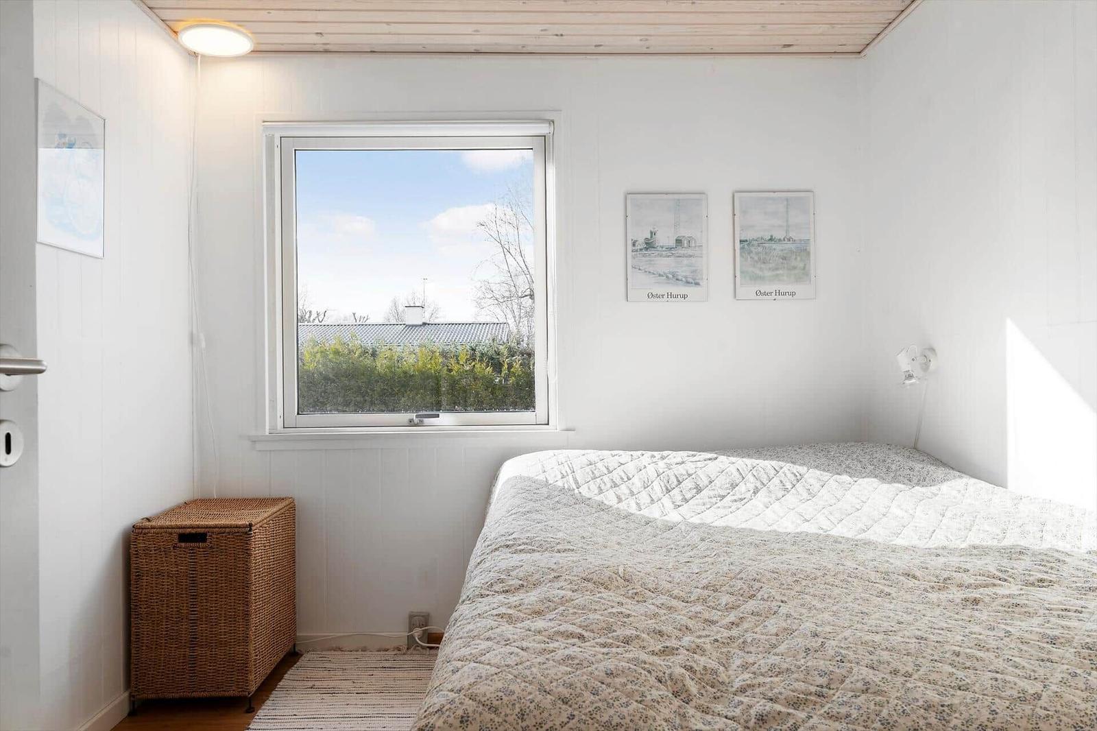 Schlafzimmer mit Bett, Fenster und Korb.