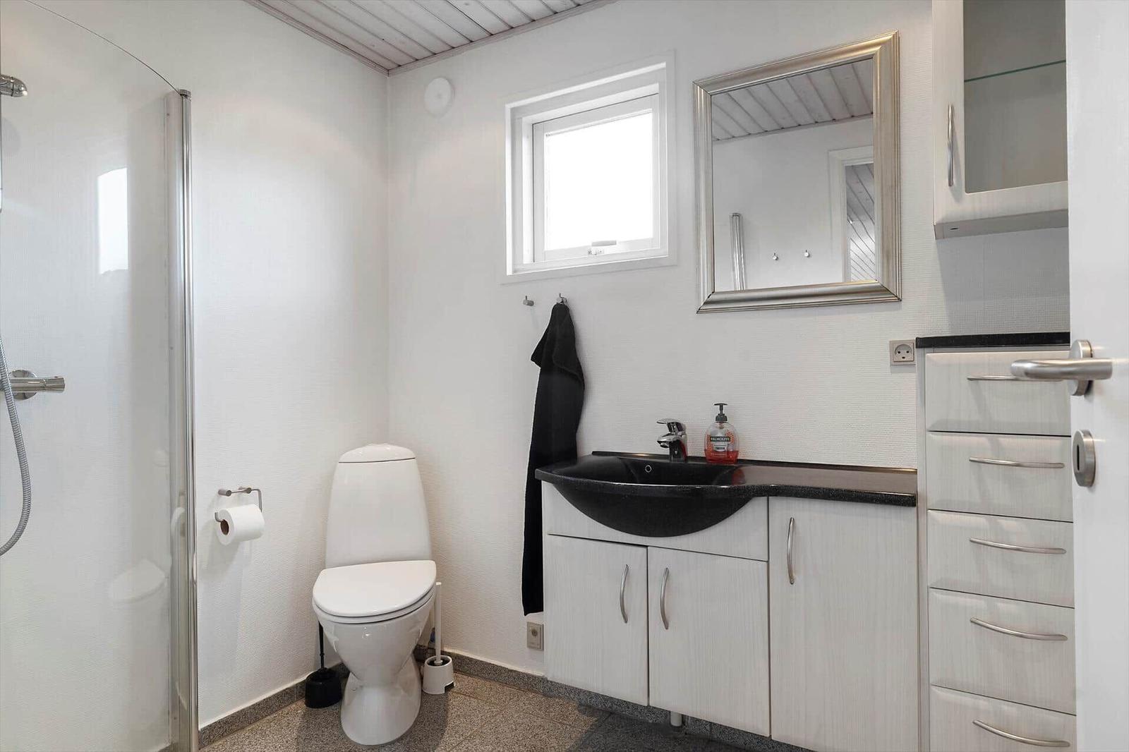 Badezimmer mit Dusche, Toilette und Waschbecken mit Spiegel.