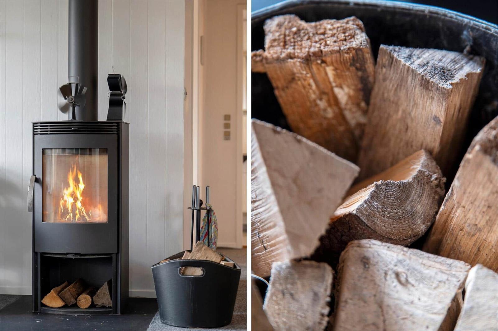 Kaminofen mit brennendem Feuer und Holzstapel daneben