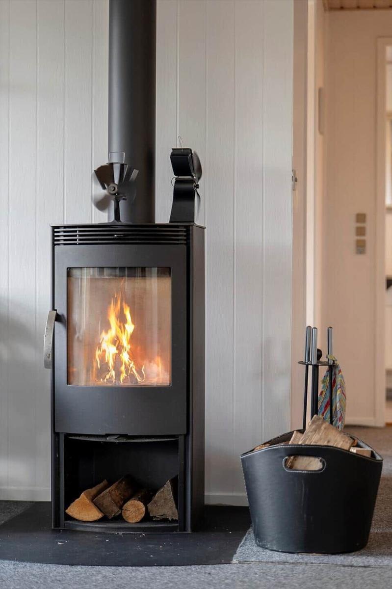 Holzofen mit brennendem Feuer und Holzkohlebehälter daneben.