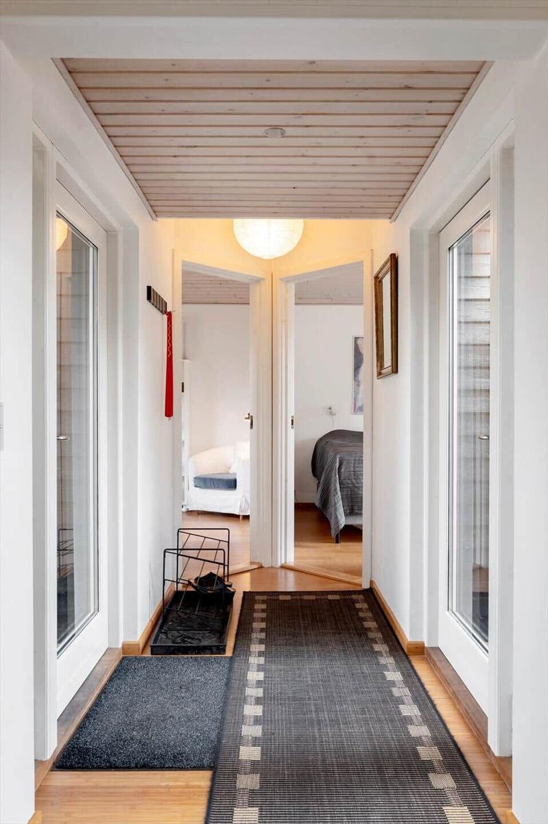 Flur mit Holzdecke, Teppich und Blick in Schlafzimmer und Wohnbereich.