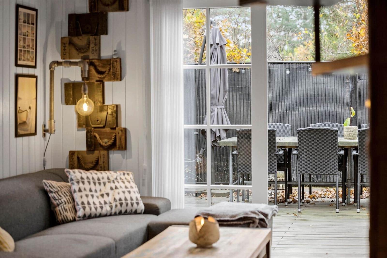 Wohnbereich mit Sofa und Blick auf Terrasse mit Tisch und Stühlen.