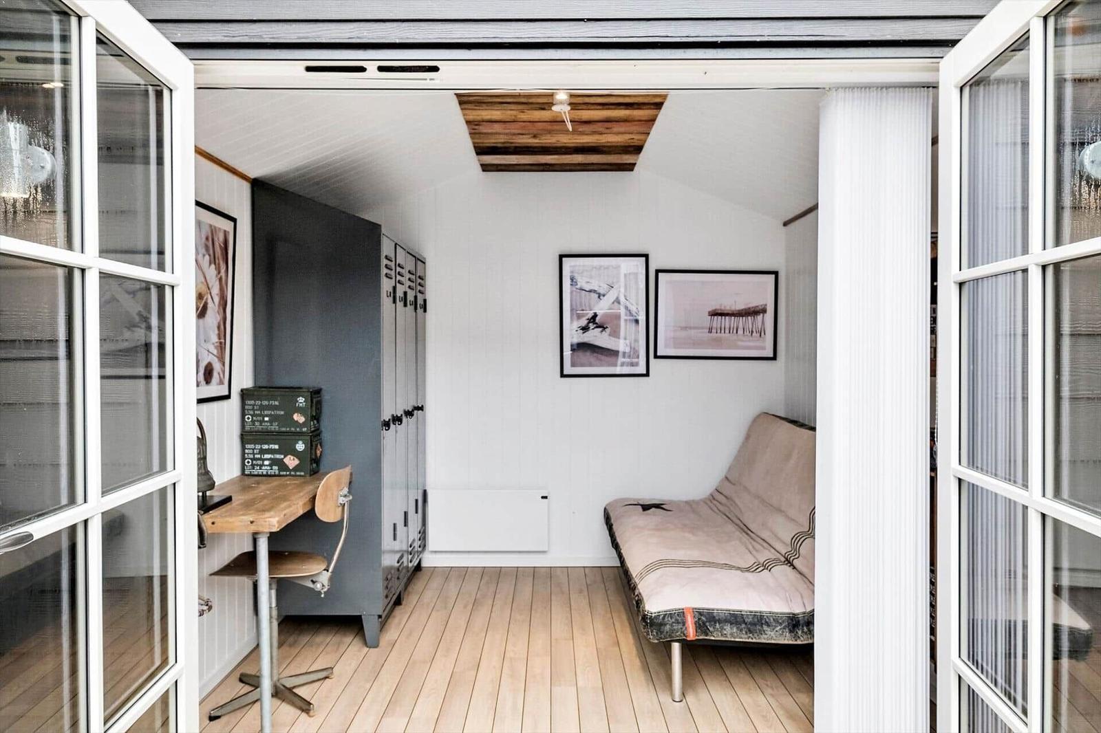 Raum mit Futon, Schreibtisch und Garderobe. Holzboden und weiße Wände.