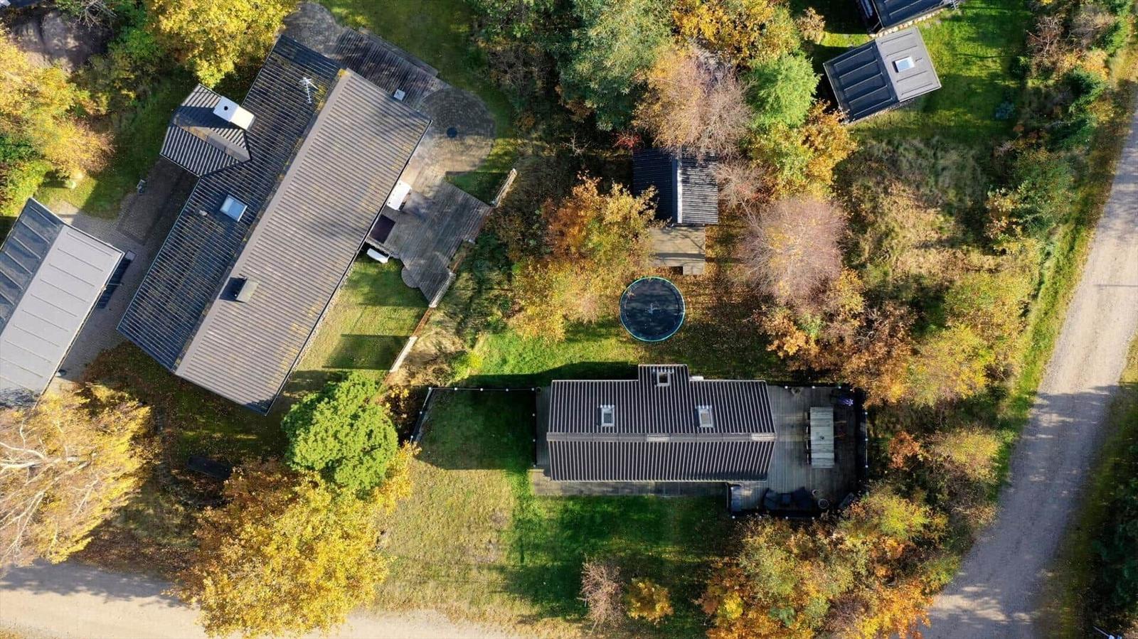 Luftbild von mehreren Häusern mit Dächern und einem runden Pool im Herbst.