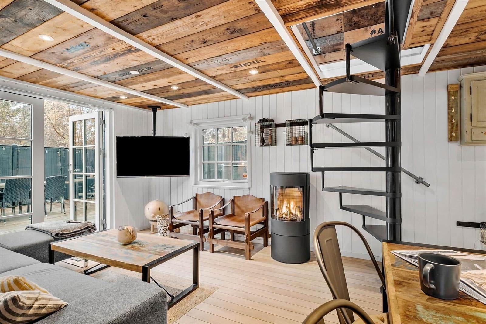 Wohnraum mit Kamin, TV und Treppe zur oberen Ebene.