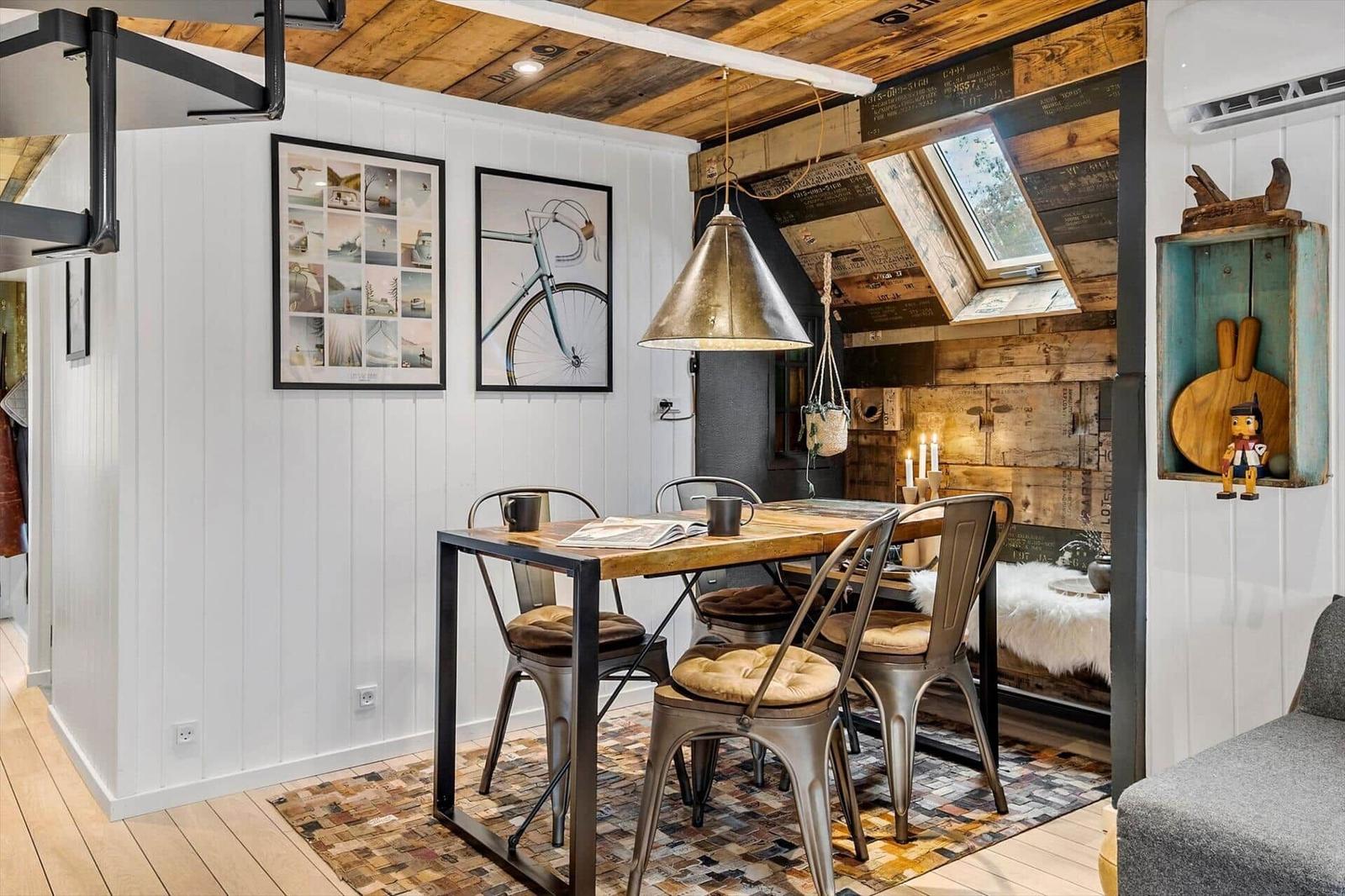 Essbereich mit Holztisch, Metallstühlen und Deckenfenster.