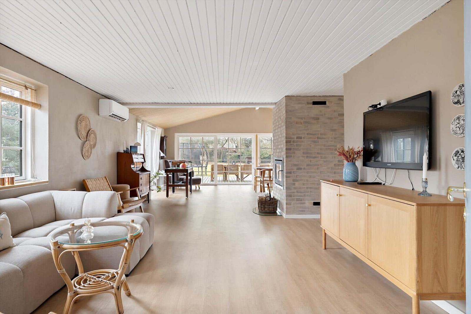 Living room with sofa, TV, and view of terrace.
