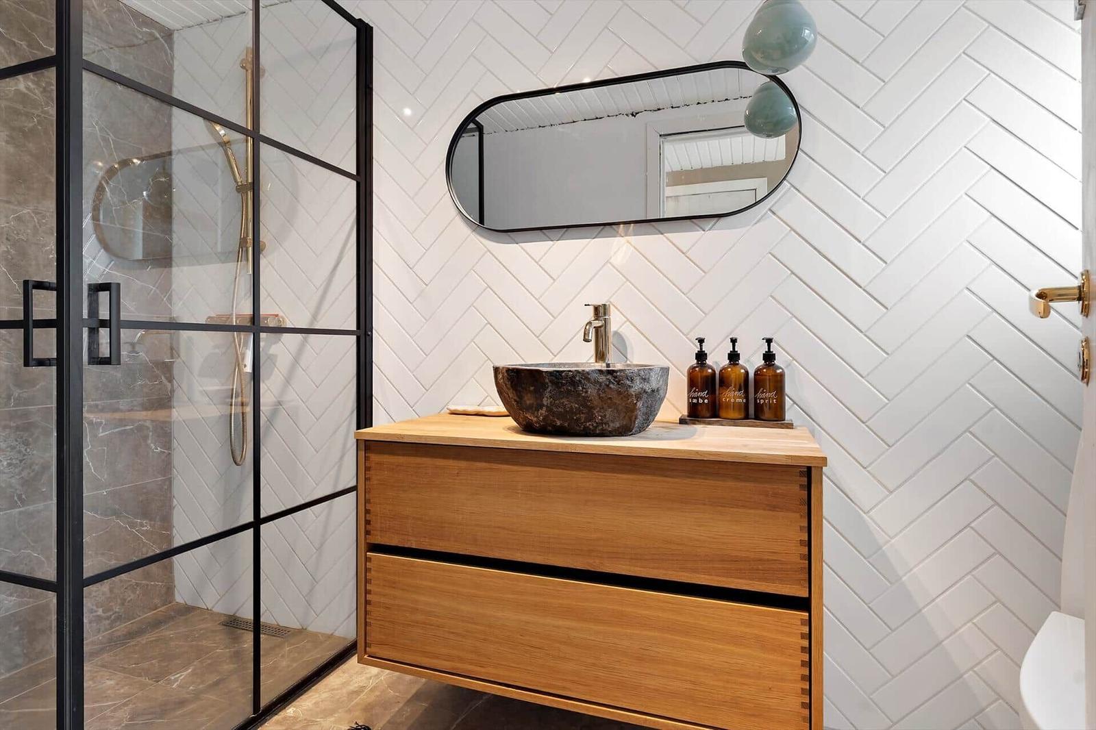 Bath with shower, sink, and mirror on herringbone wall