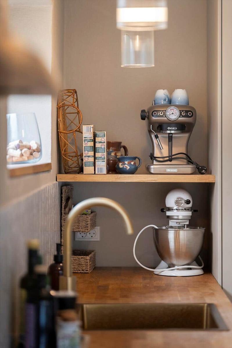 Kitchen area with coffee machine and stand mixer on wooden shelf.