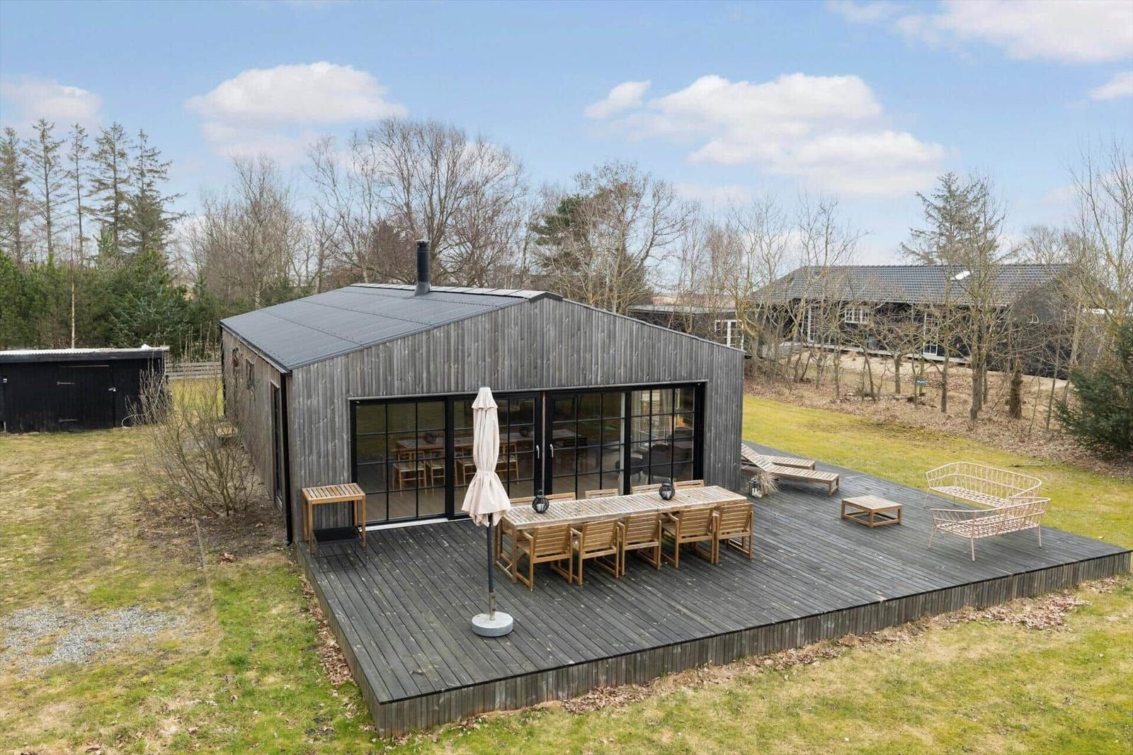 Modern wooden cabin with large terrace area and garden.