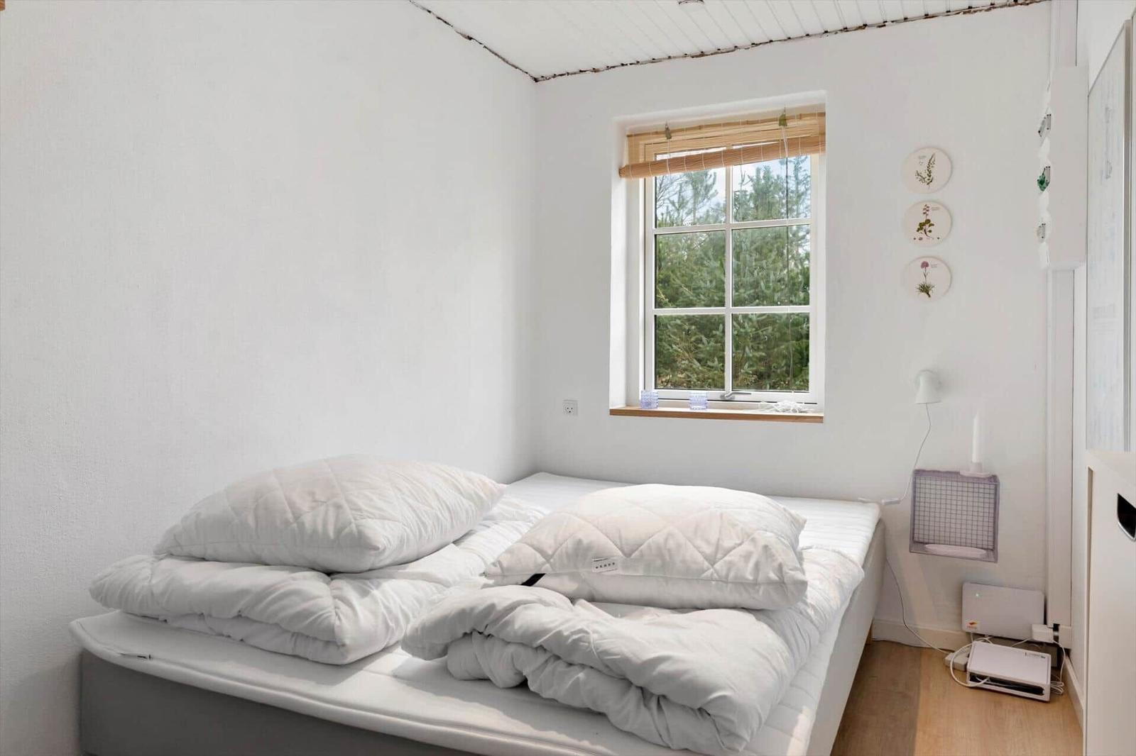 Bedroom with bed, window, and wall decor.
