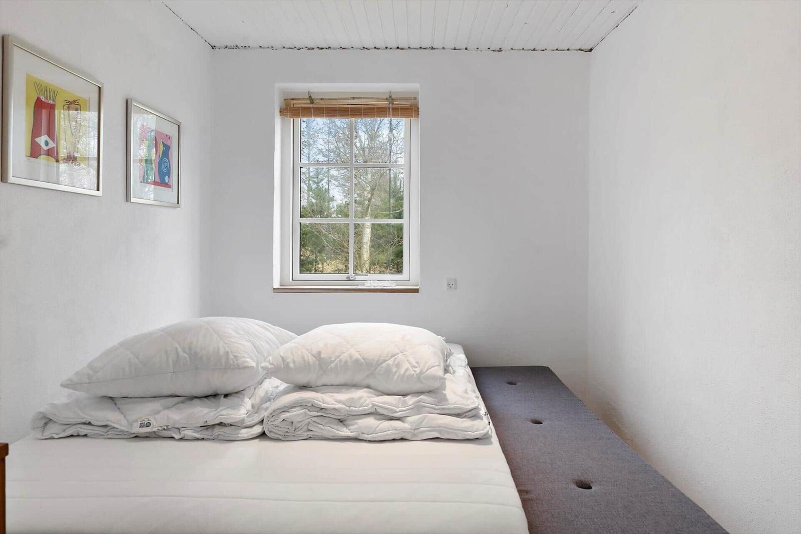 Bedroom with bed, window, and art on the wall.