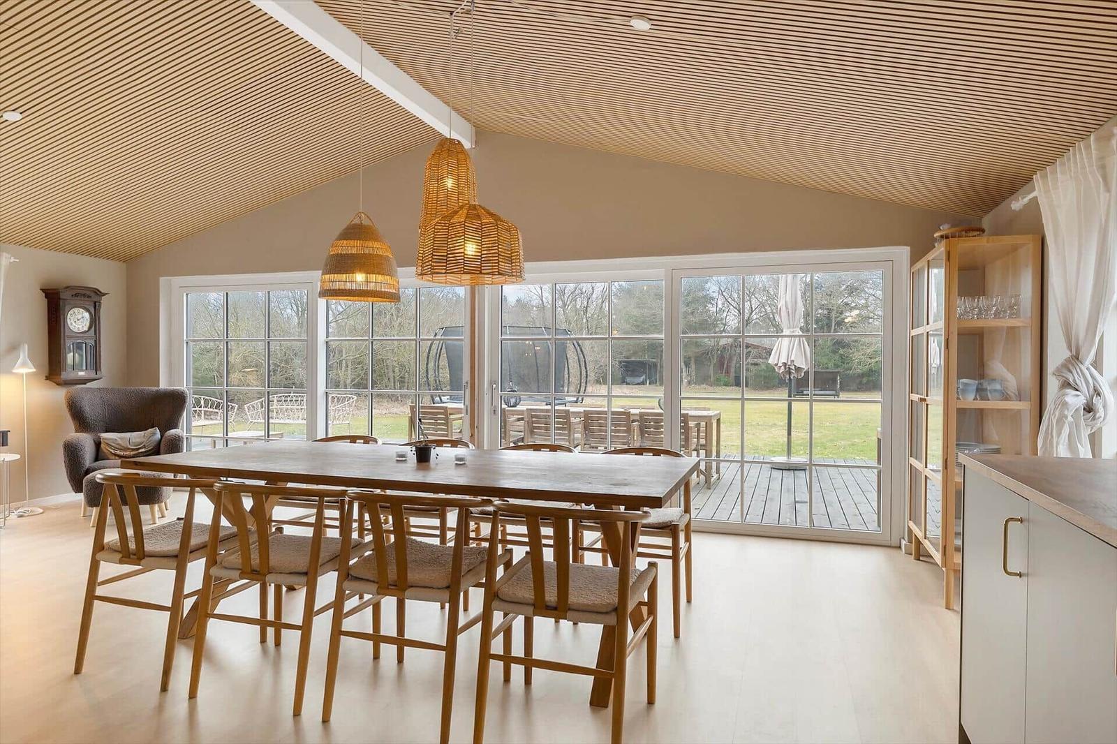 Dining room with wooden table, chairs, and large windows to the garden.