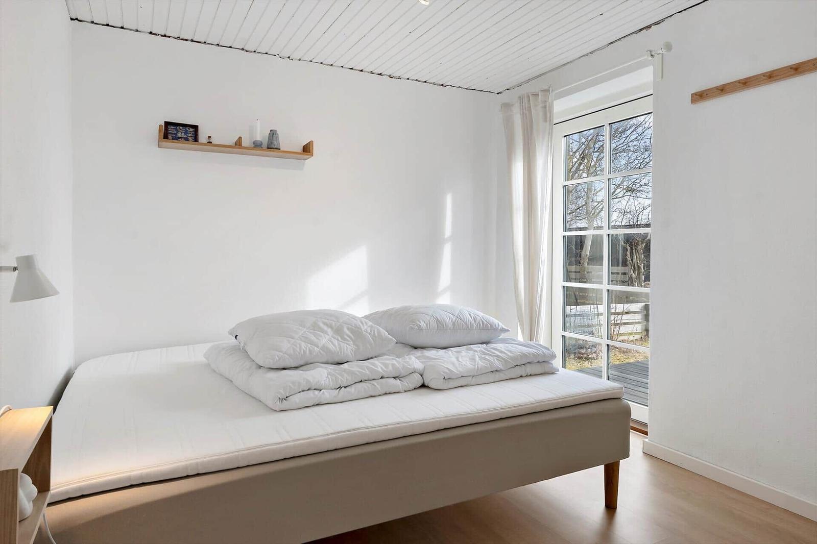 Bedroom with bed, window, and wooden floor.