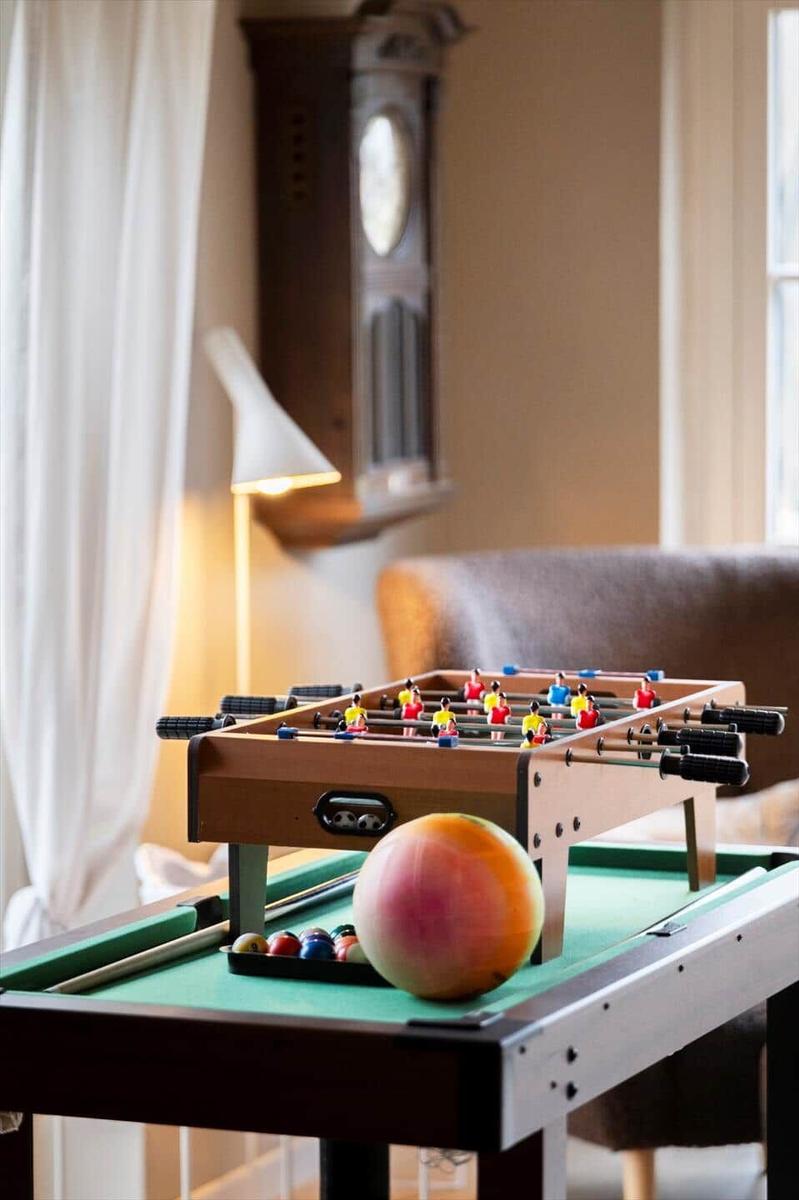 Foosball table on green pool table with balls and a fruit