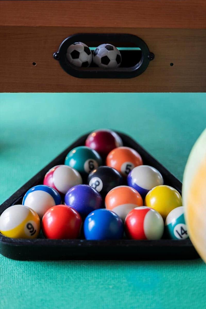 Pool table with balls in triangle and two soccer balls in compartment.