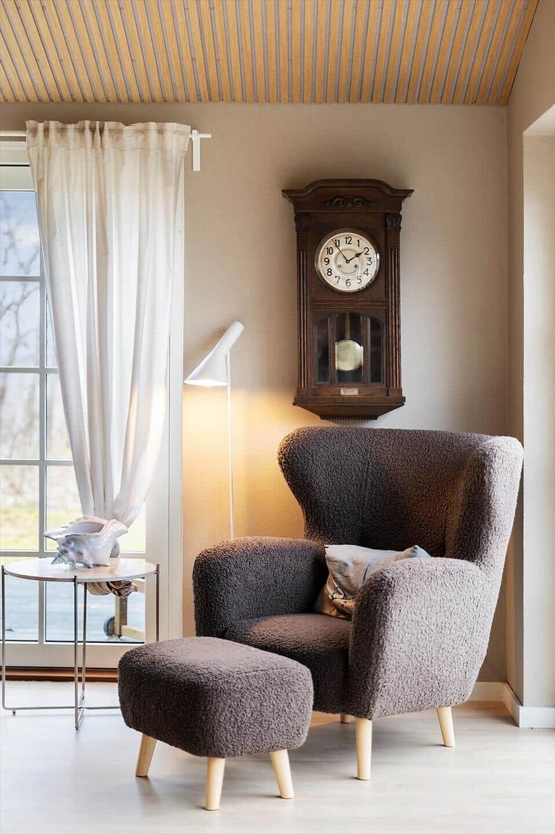 A room with a brown armchair, a side table, and a wall clock.