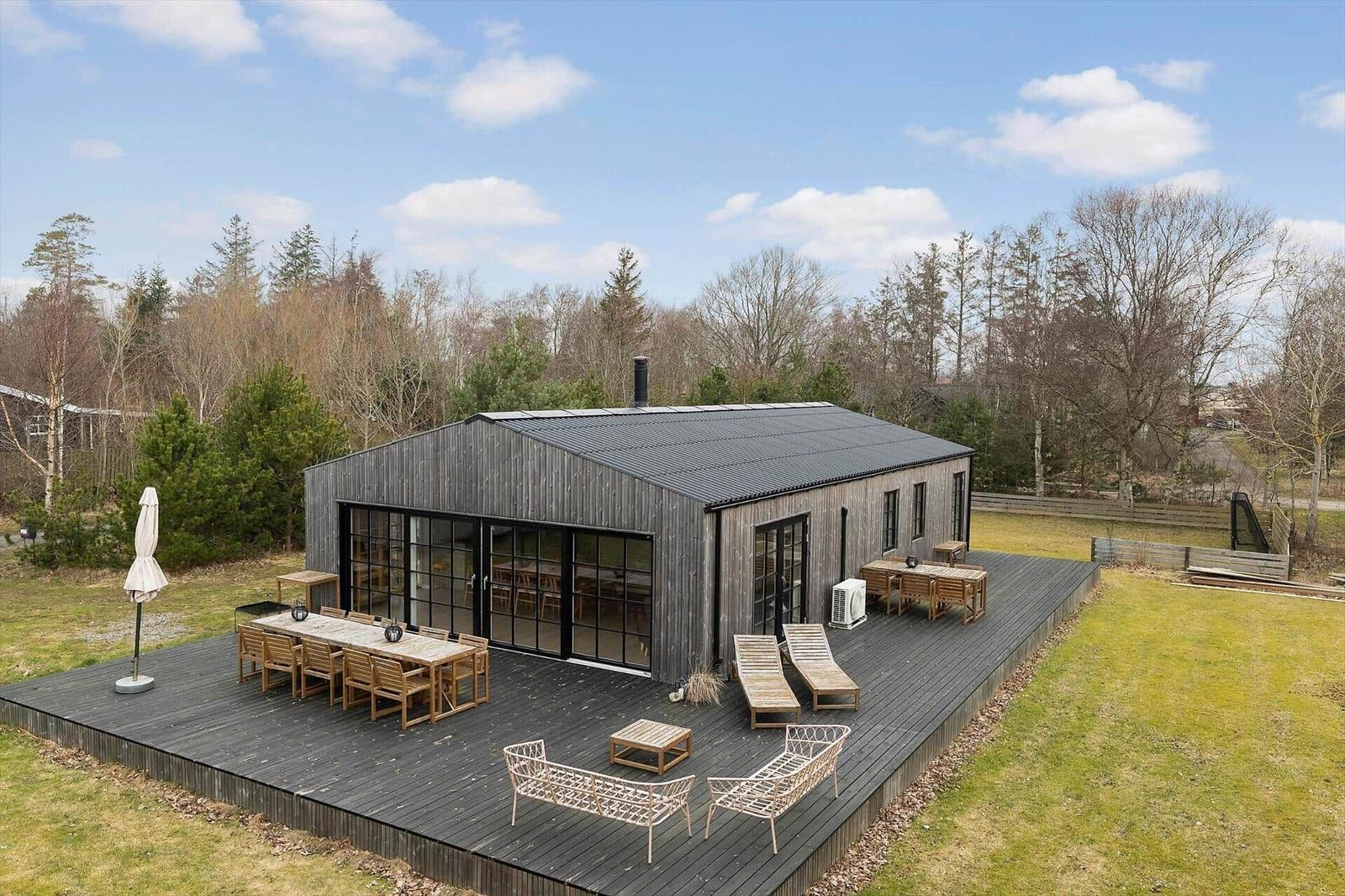 Modern wooden cabin with large terrace and garden.