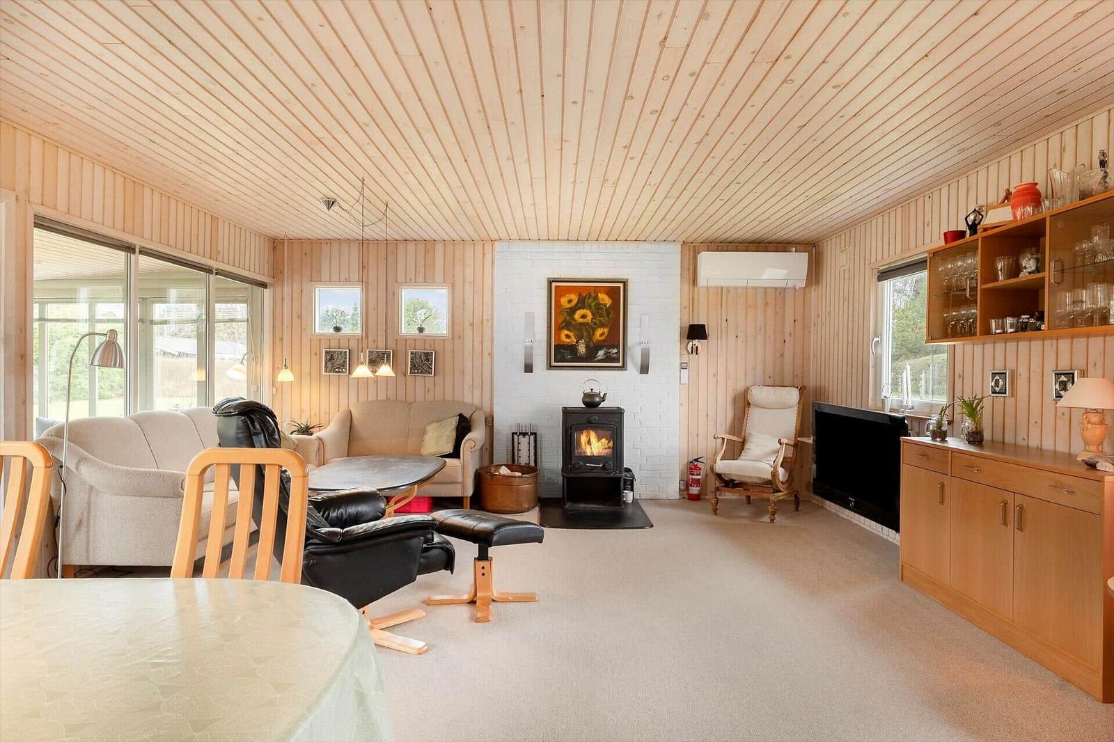 Living room with fireplace, sofa, chairs, and wood paneling.