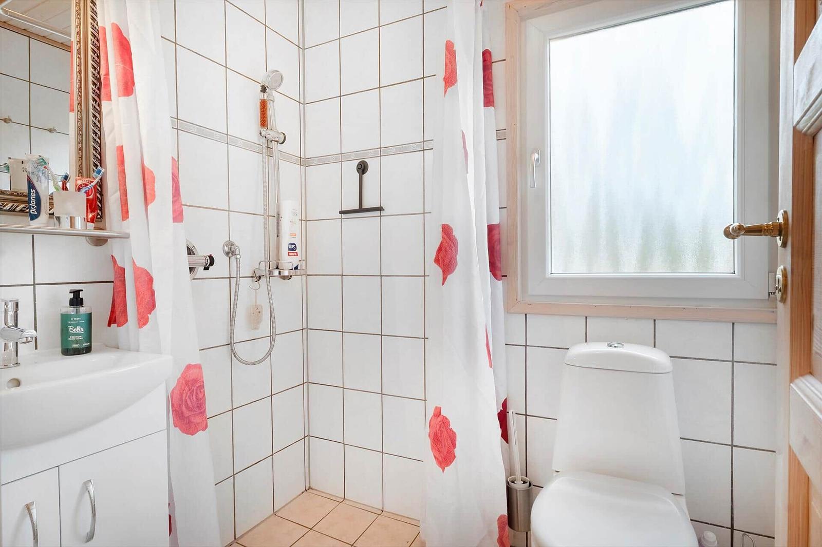 Bathroom with shower, toilet, and sink. Window with frosted glass.