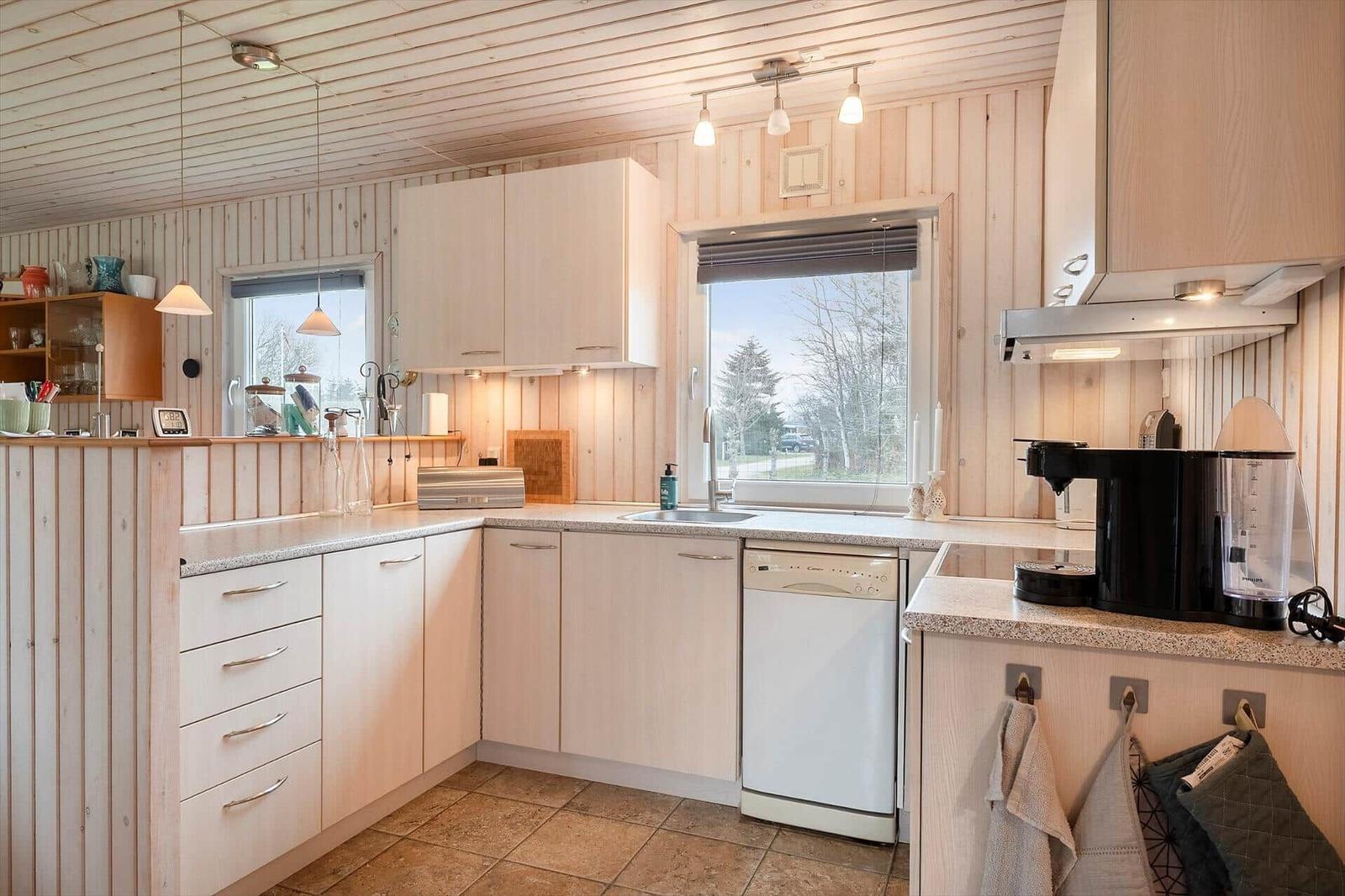 Kitchen with wooden walls, sink, dishwasher, and window