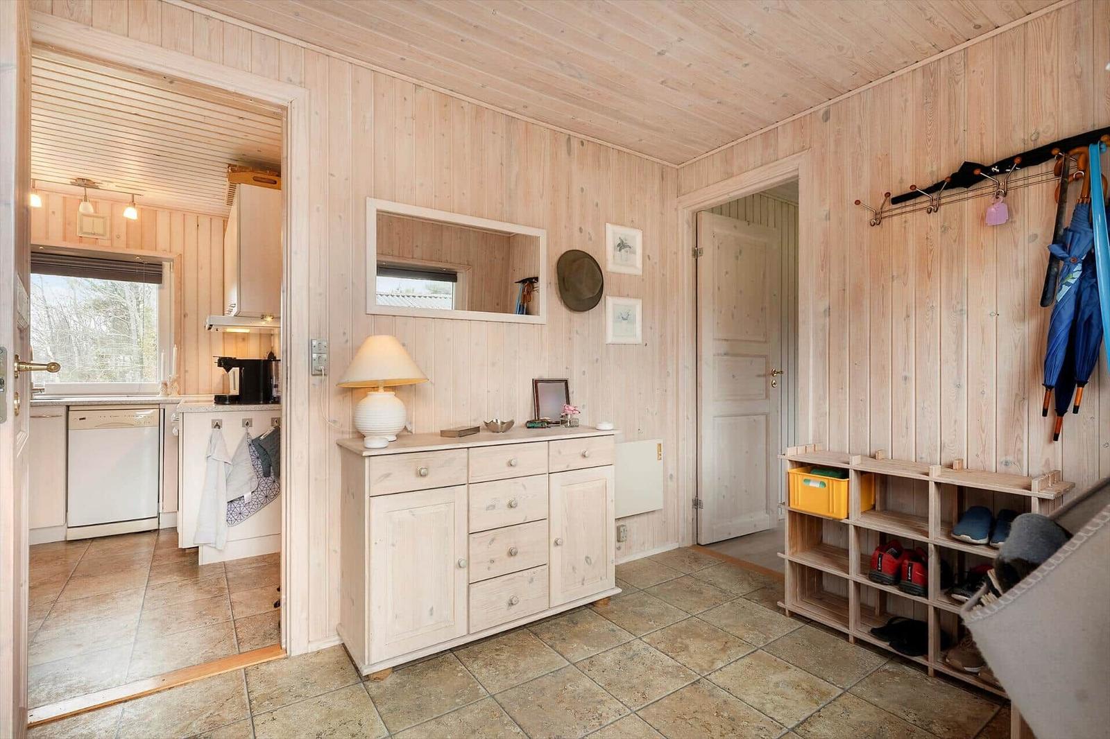 Entrance area with shoe rack, coat hooks, and view into the kitchen.