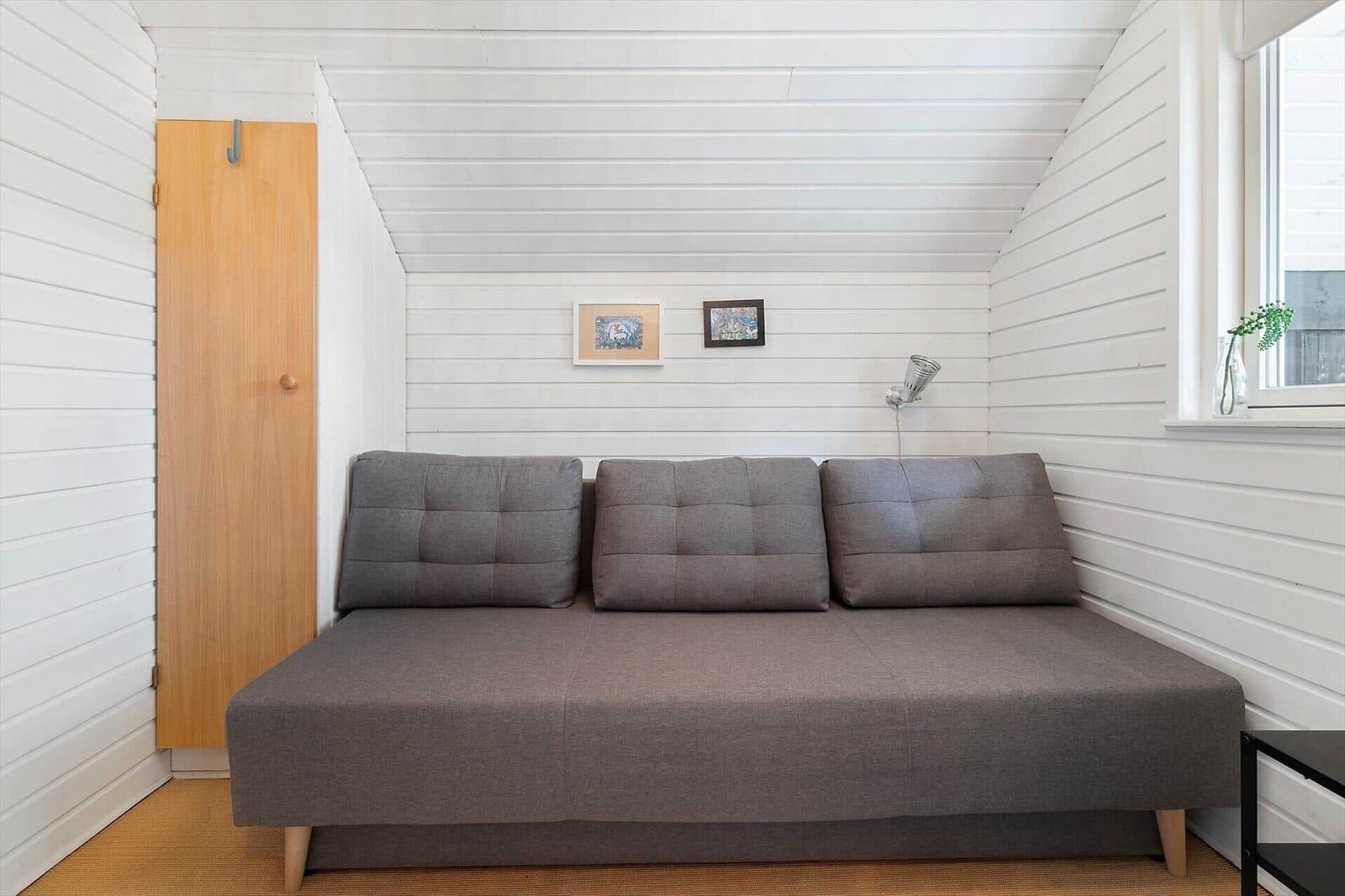 A gray sofa bed in a room with white walls and a window.