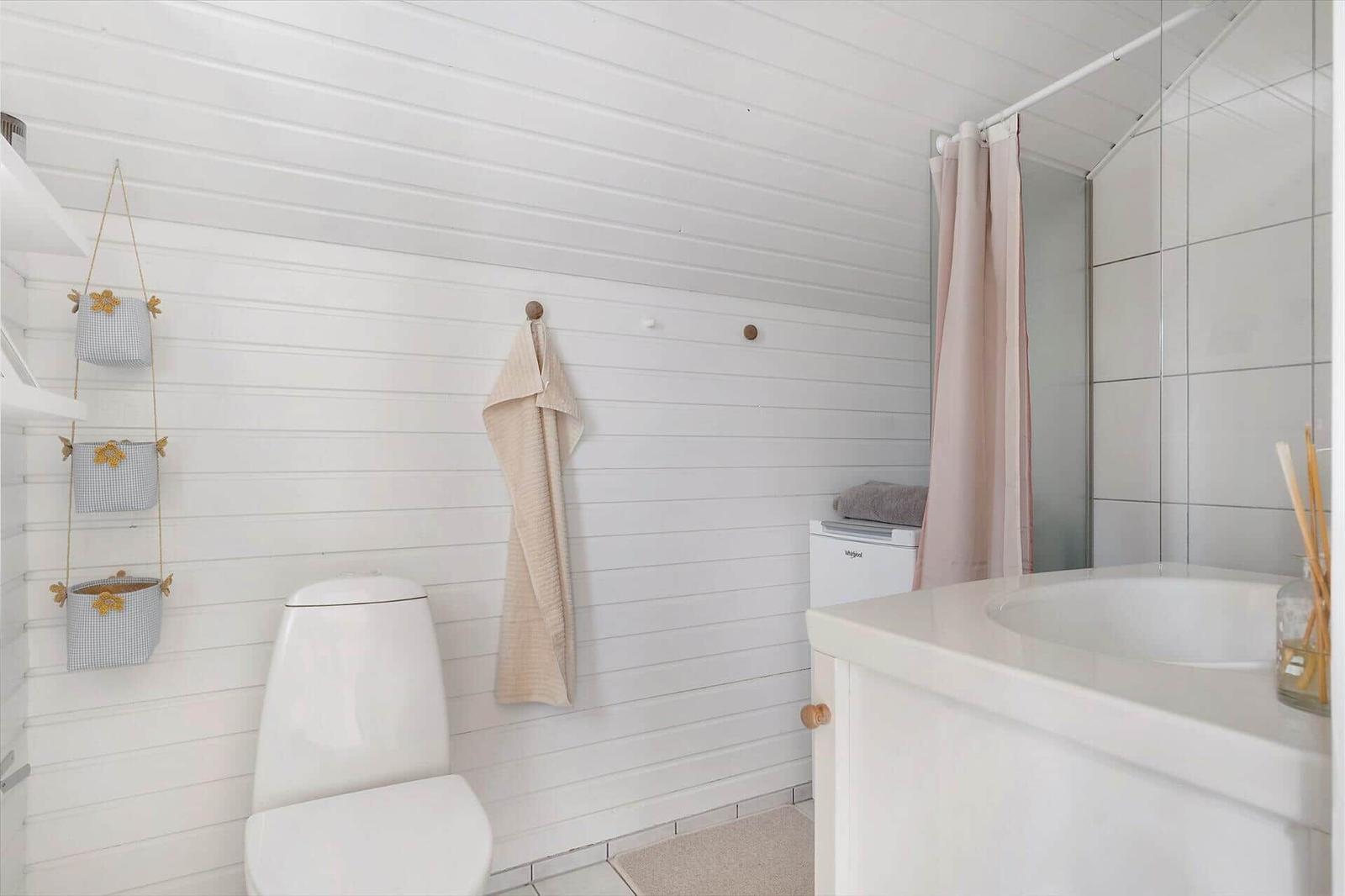 Bathroom with toilet, sink, and shower with pink curtain.
