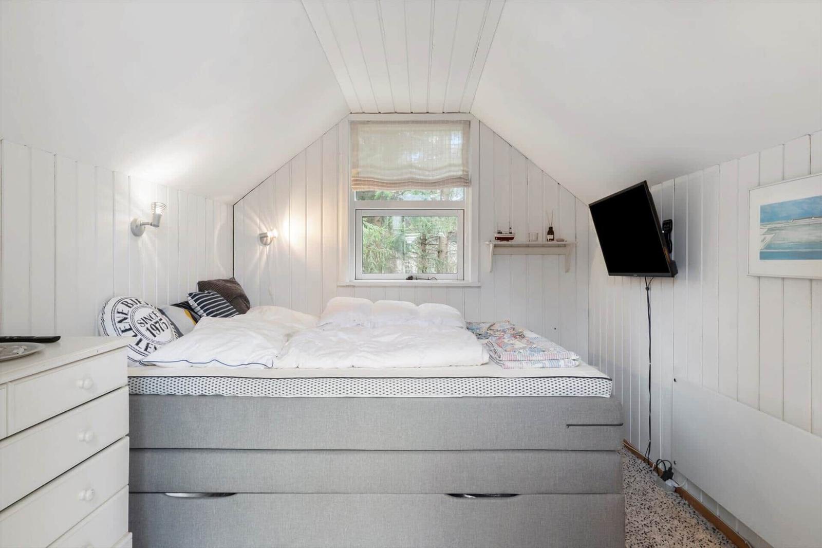Bedroom with bed, window, and wall-mounted TV.