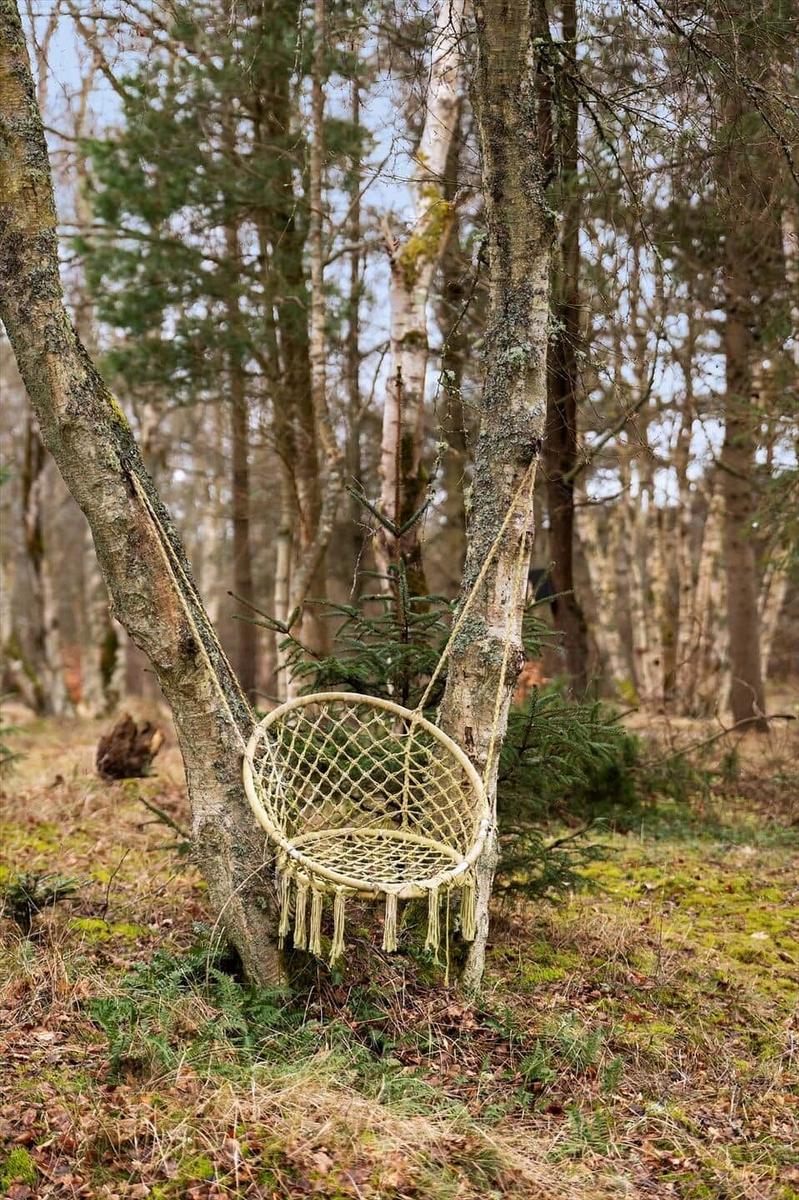 Hanging chair made of woven material between two trees in the forest