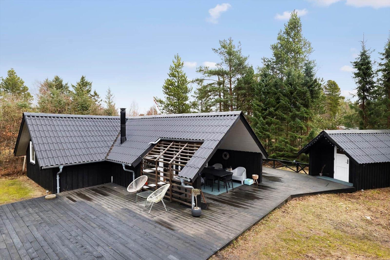 Black wooden house with terrace and grill area in the woods