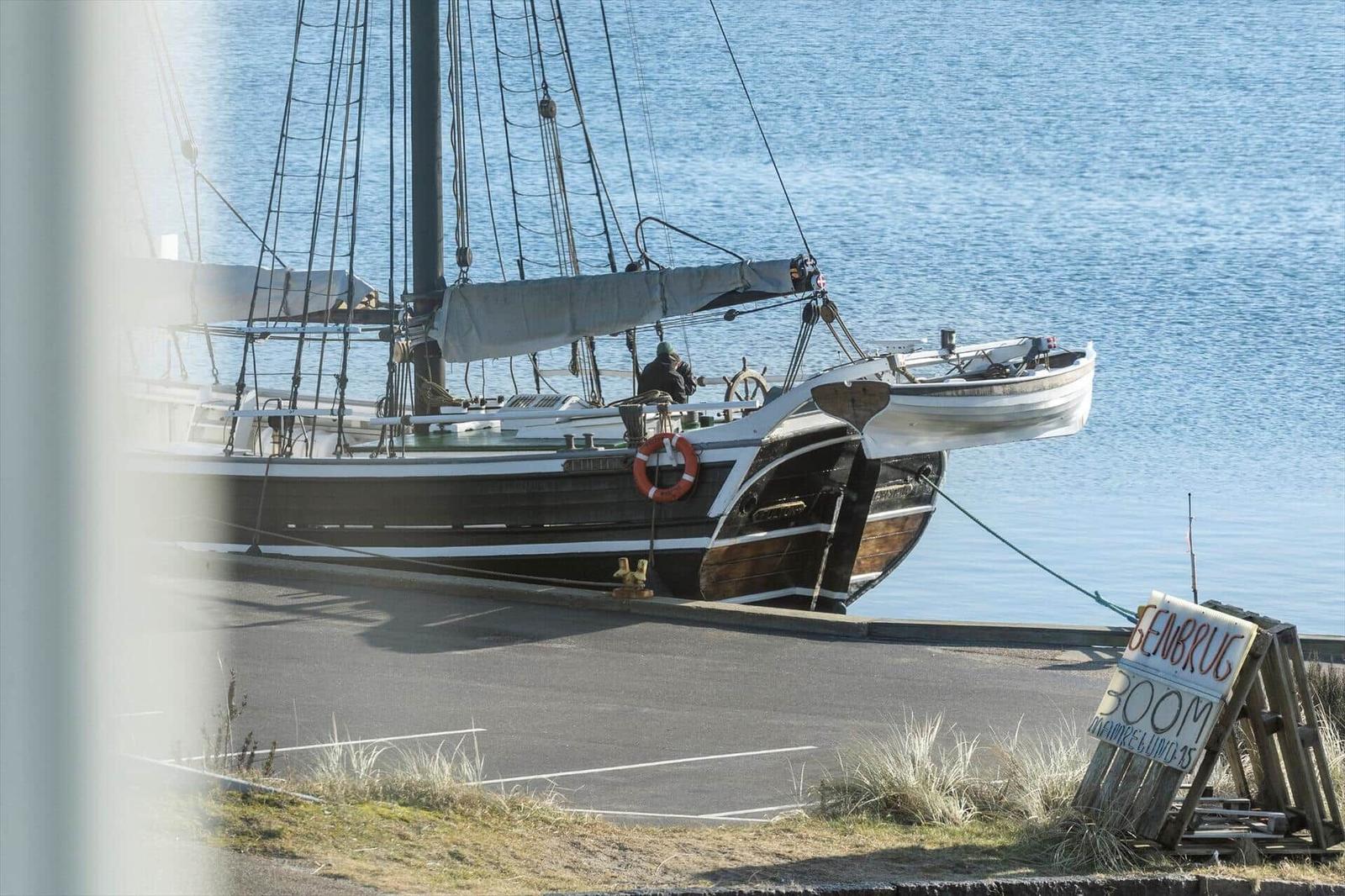 Segelschiff am Hafen mit Steuerrad und Rettungsring.