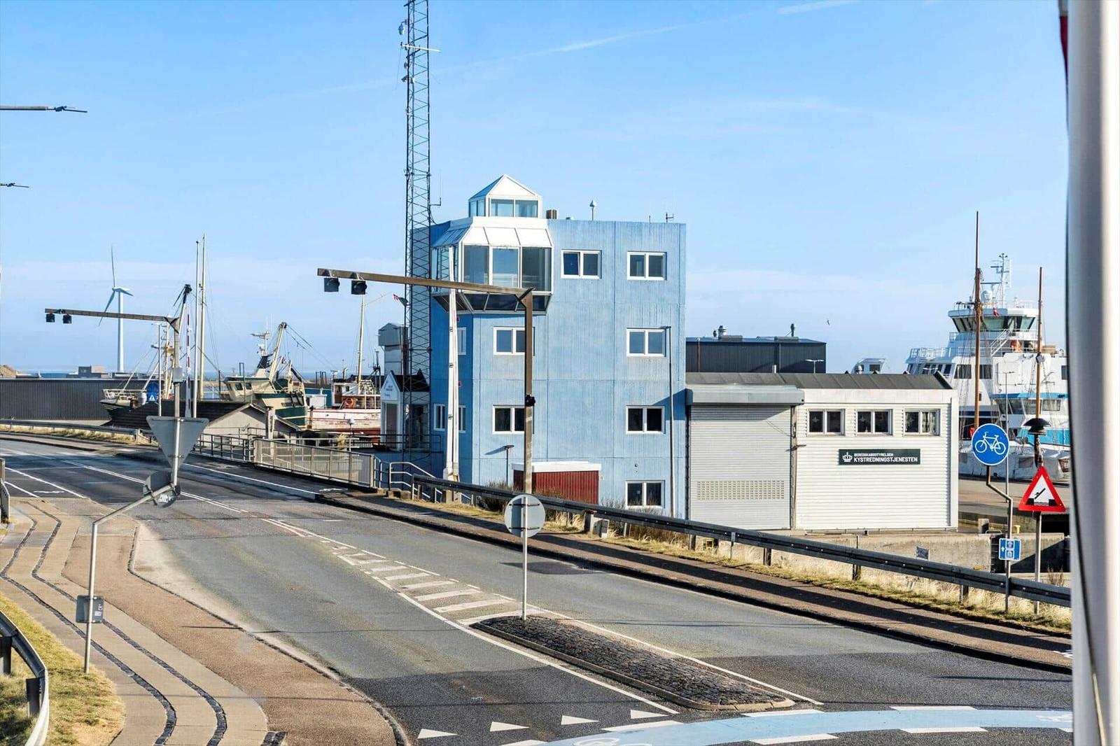 Blauer Turm neben Hafen mit Booten und Windkraftanlagen