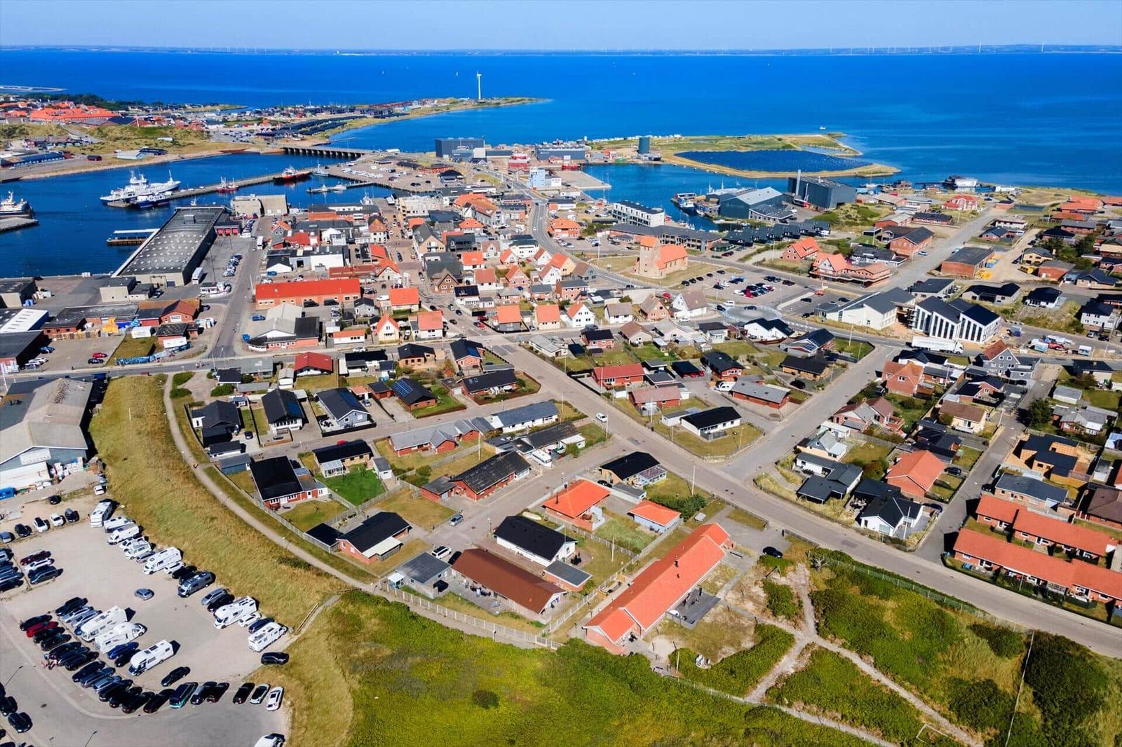 Aerielansicht von Küstenstadt mit Häusern, Hafen und blauem Meer.
