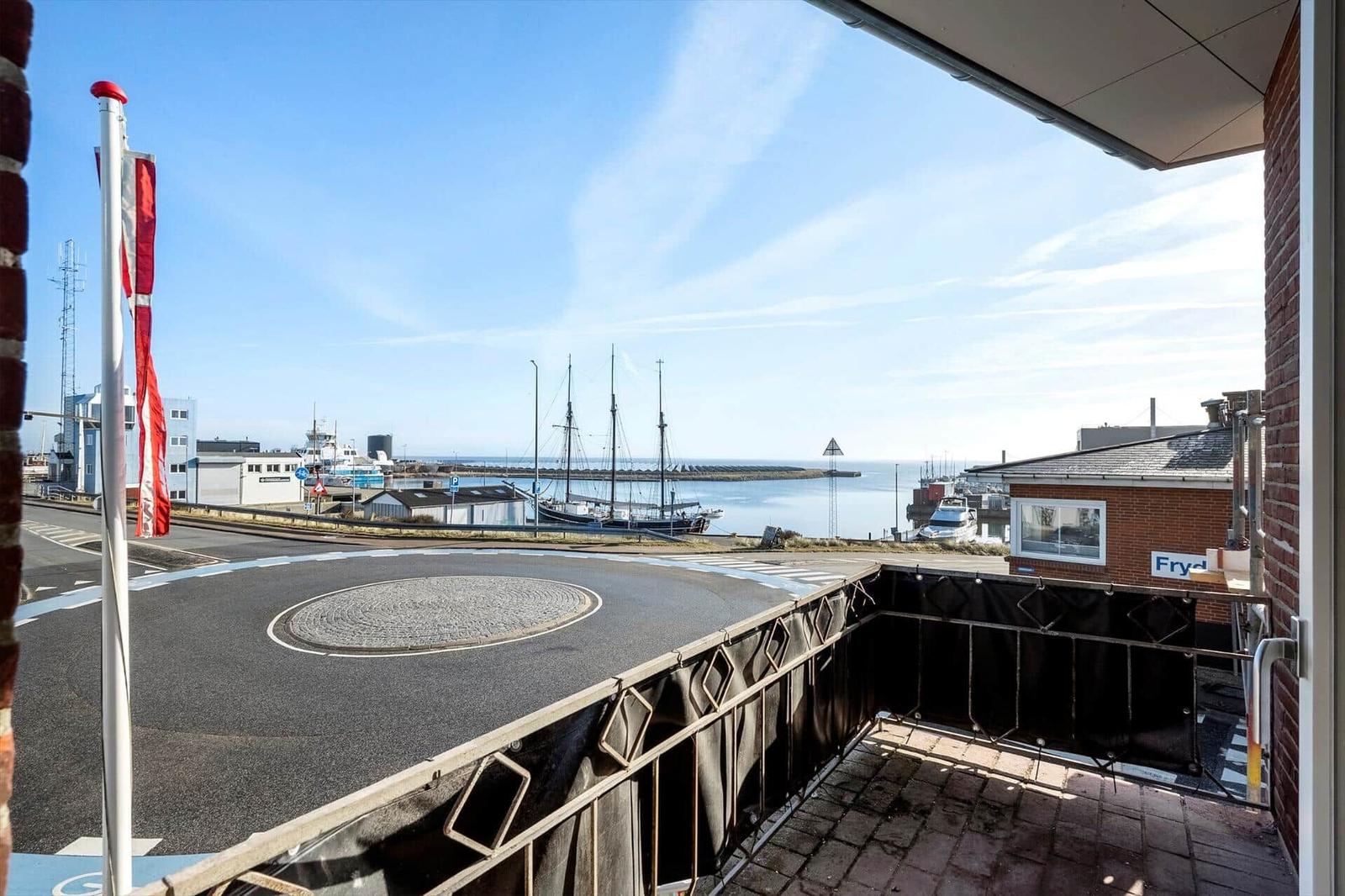 Blick vom Balkon auf Hafen mit Schiffen und Strand.