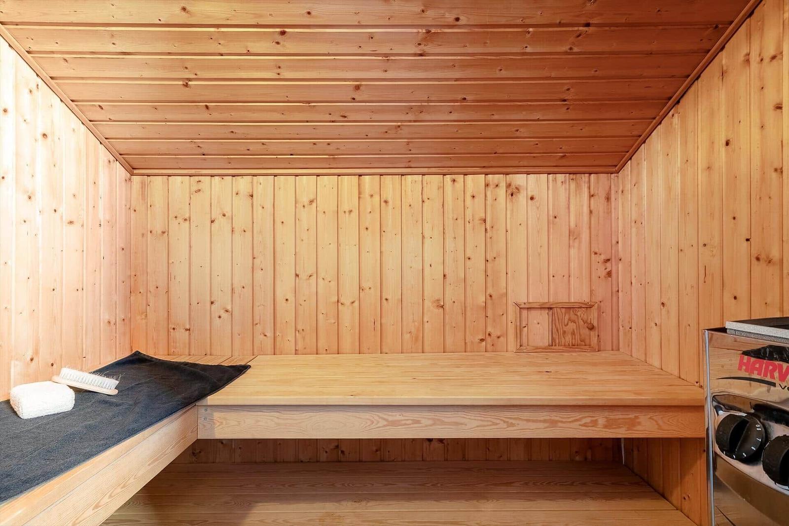 Holzsauna mit Sitzbank, Handtuch und Bürste. Heizung rechts.