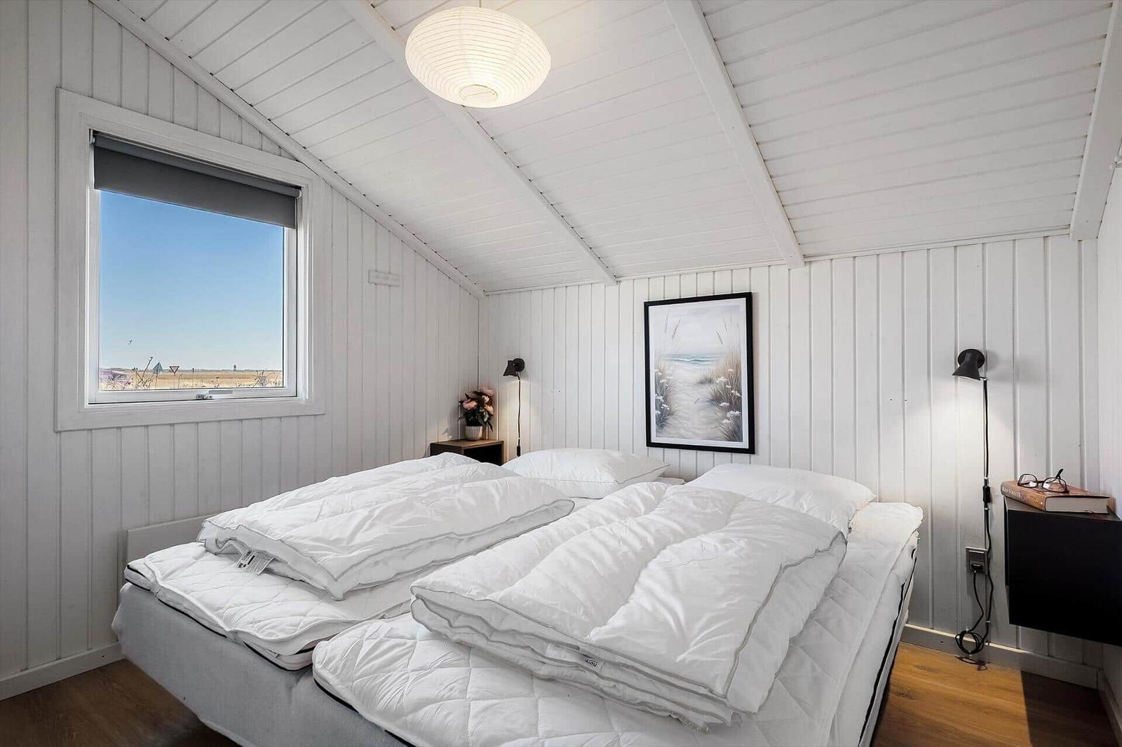 Schlafzimmer mit Doppelbett, Fenster und Wandbild.
