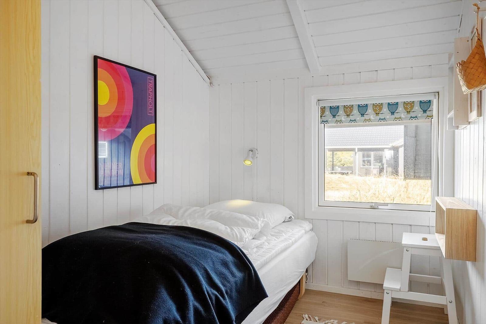 Schlafzimmer mit Bett, Fenster und Wandbild.
