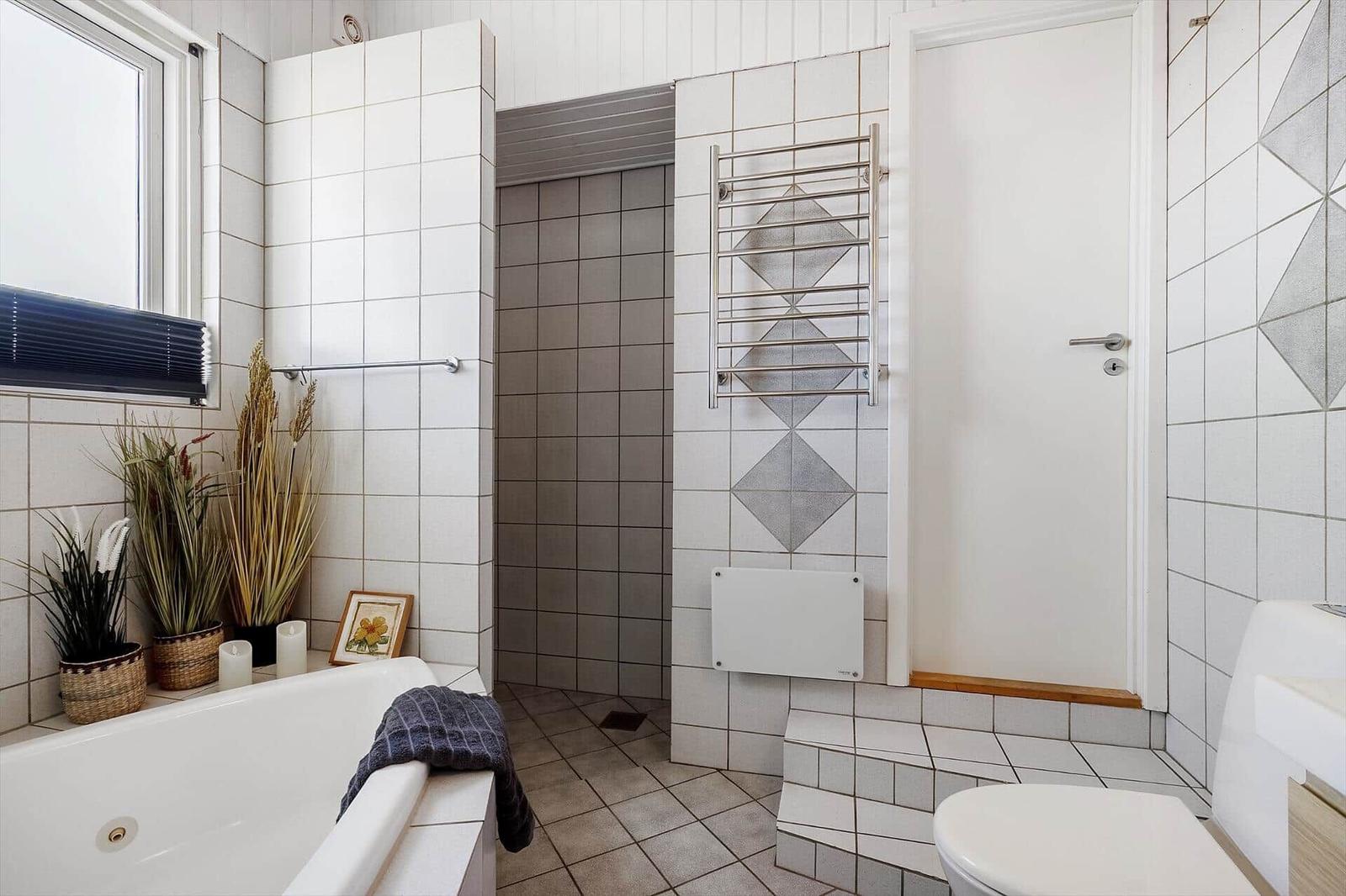 Badezimmer mit Badewanne, Dusche, Toilette und Fenster.