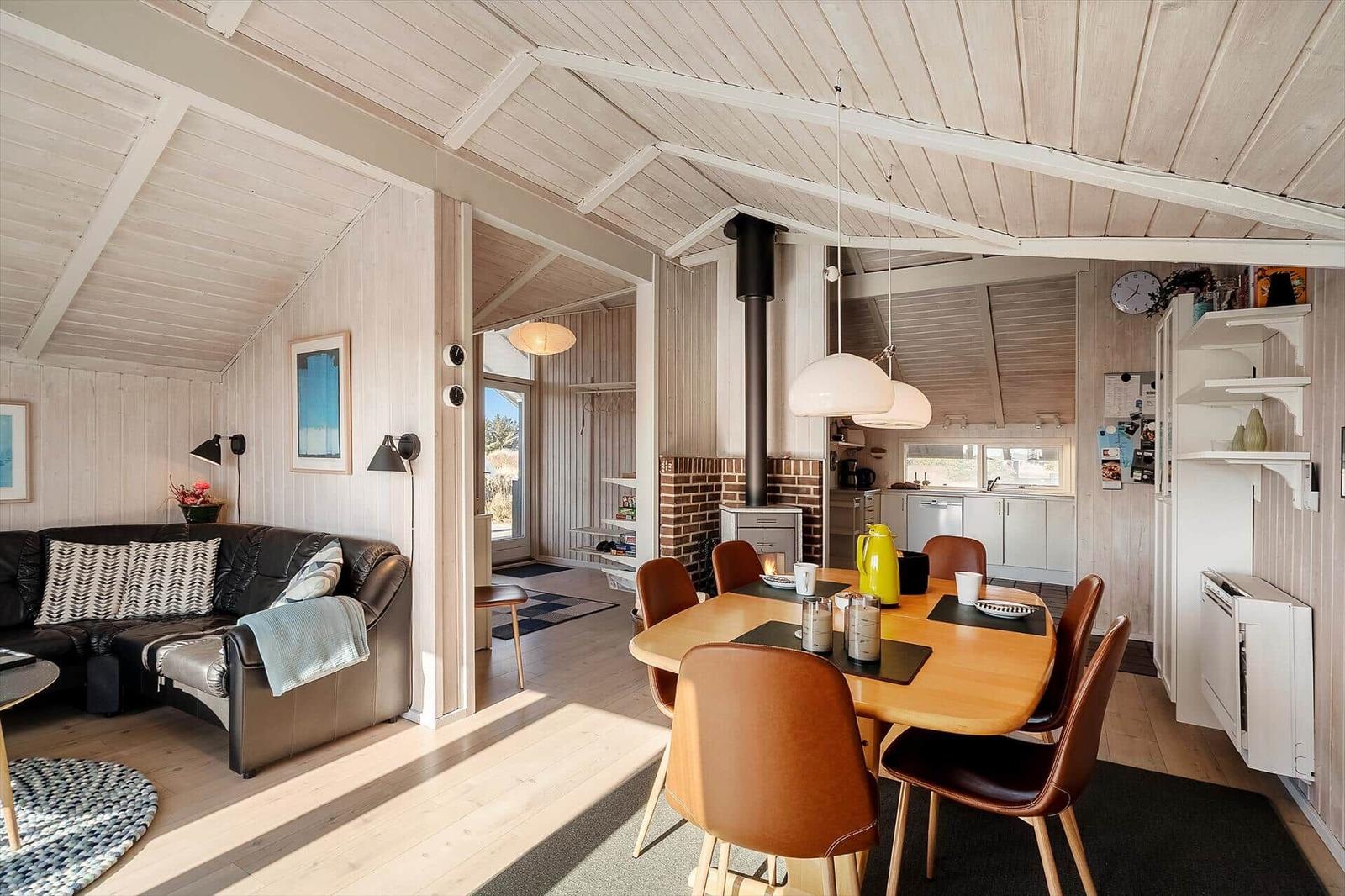 Wohn- und Essbereich mit Holzdecke, Esstisch und Sofa.