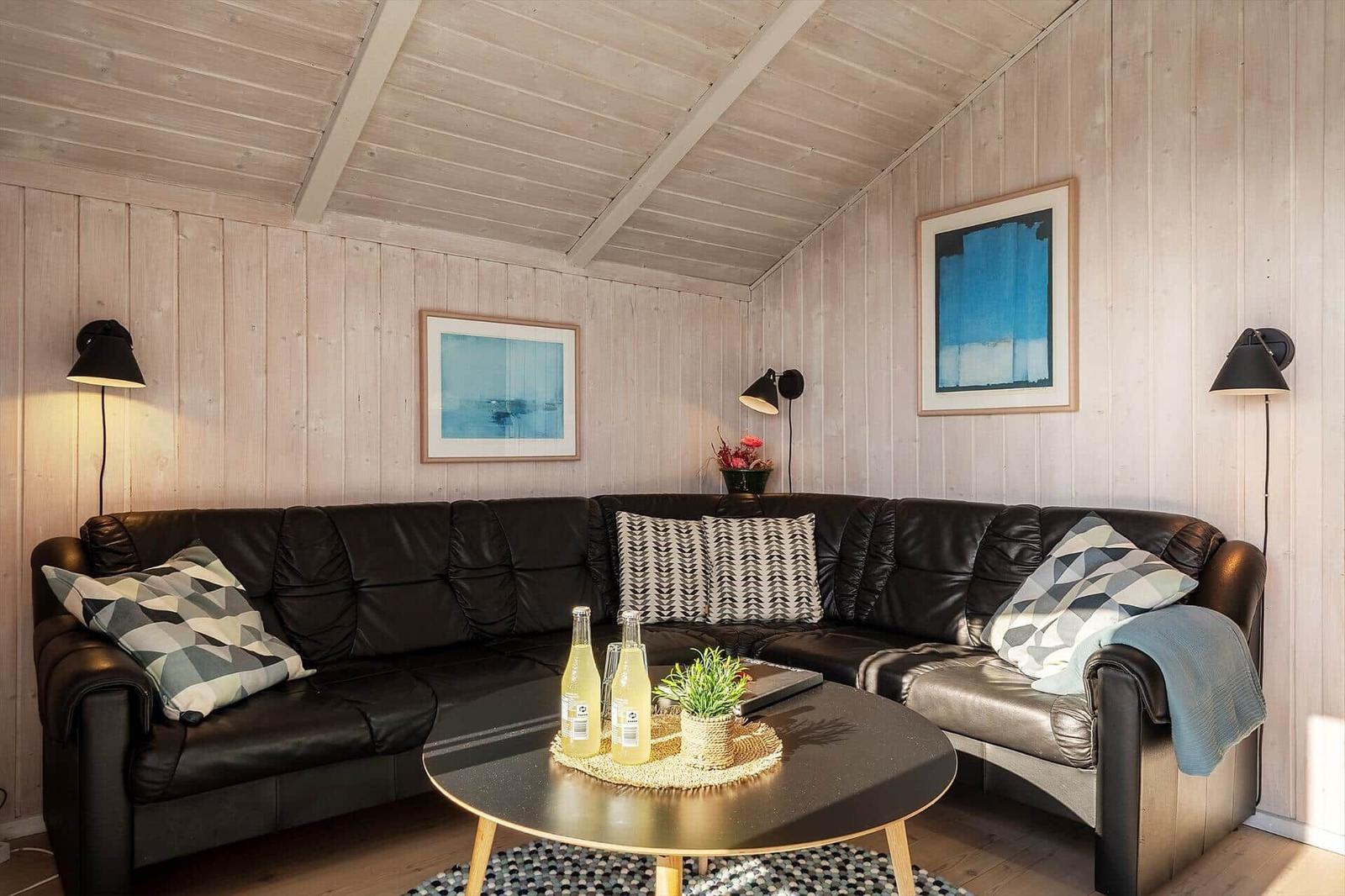 Schwarzes Sofa mit Kissen, runder Tisch und Holzwand im Wohnzimmer.