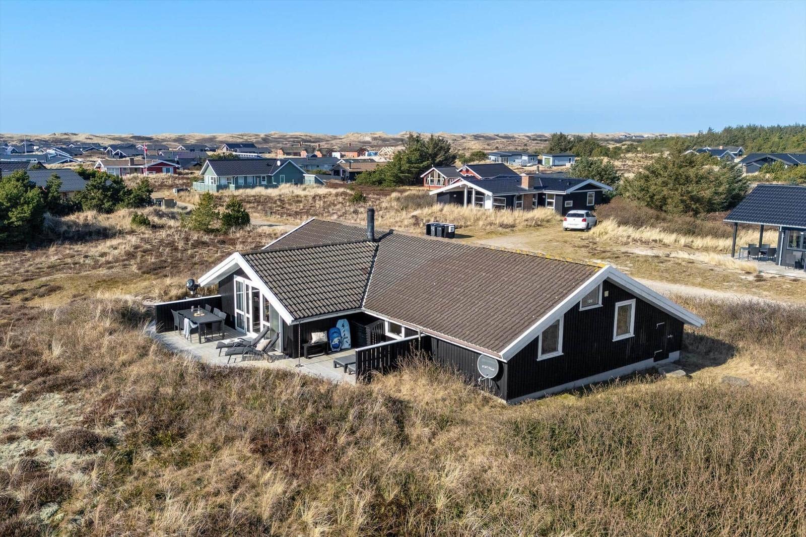 Schwarzes Ferienhaus mit Terrasse und Blick auf Dünenlandschaft