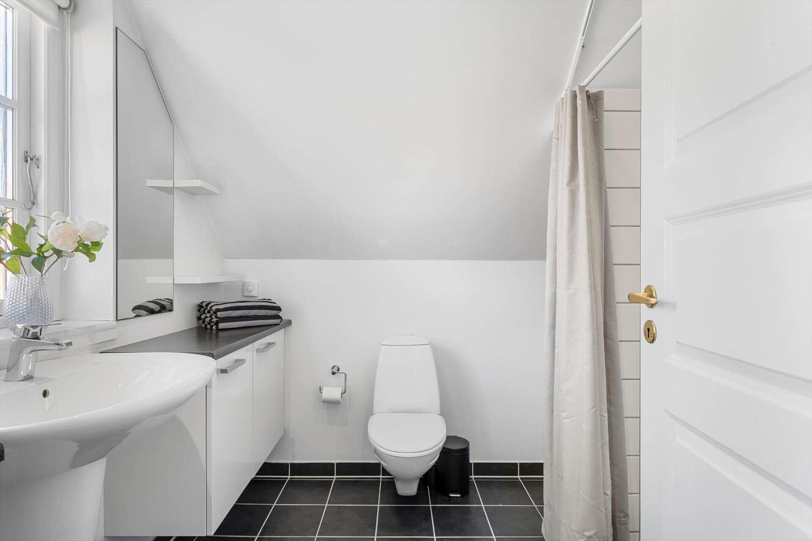 Badezimmer mit Waschbecken, Toilette und Duschvorhang.
