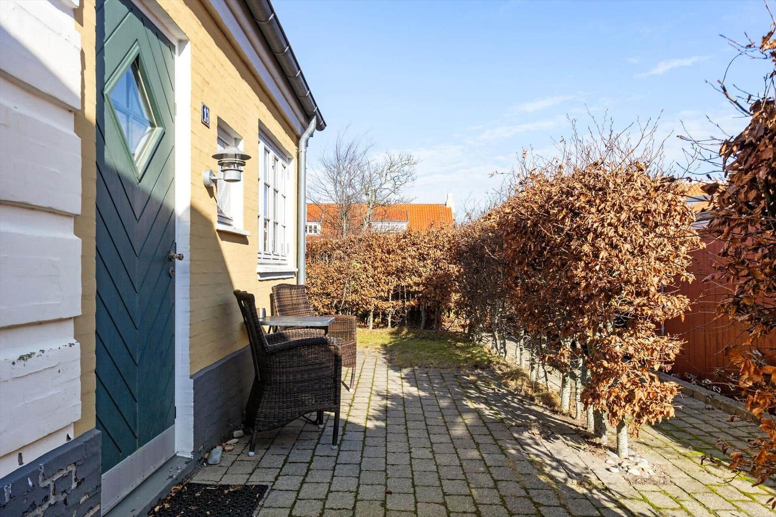 Haus mit grüner Tür, Terrasse und Garten mit Bäumen.